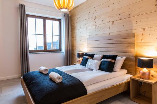 een slaapkamer met een houten accentmuur en een bed met kussens bij udanypobyt Apartamenty Czorsztyn Panorama in Czorsztyn