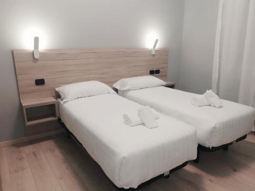 two beds in a room with white sheets at Miu Hotel in Milan