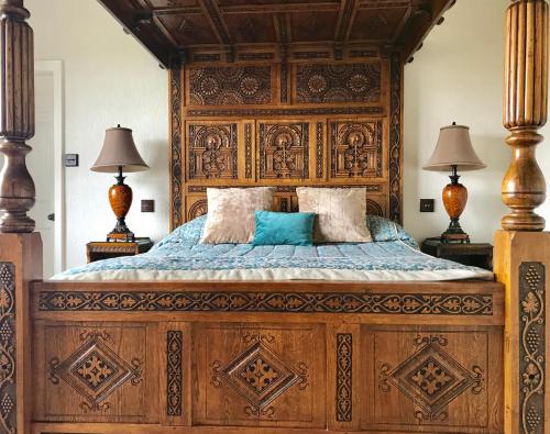 a bedroom with a large wooden bed with two lamps at Loftsome Bridge Hotel in Wressell