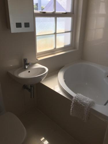 ein Badezimmer mit Waschbecken, Badewanne und Fenster in der Unterkunft Strandview Ground Floor Beach Apartment in Ballycastle