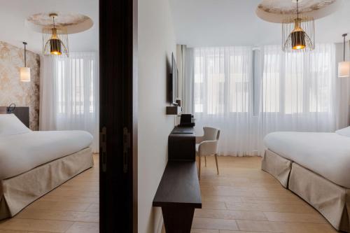 a bedroom with two beds and a desk in it at Hotel L'Arbre Voyageur - LILLE in Lille