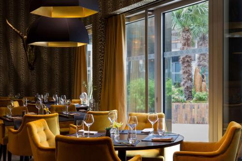 un restaurant avec des tables et des chaises et une grande fenêtre dans l'établissement Hotel L'Arbre Voyageur - BW Premier Collection - LILLE, à Lille