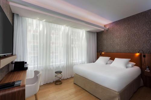 a bedroom with a white bed and a large window at Hotel L'Arbre Voyageur - LILLE in Lille