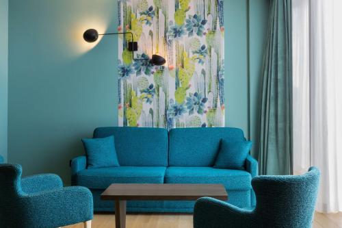 a living room with a blue couch and two chairs at Hotel L'Arbre Voyageur - LILLE in Lille