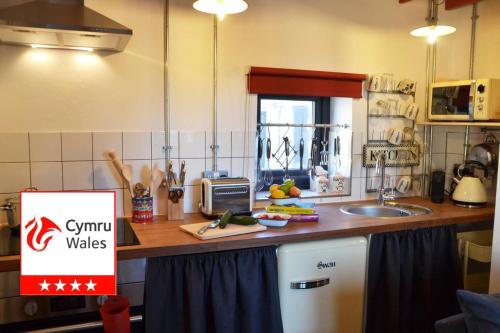 a kitchen with a sink and a counter with a sign at Grain Store Cottage in Narberth