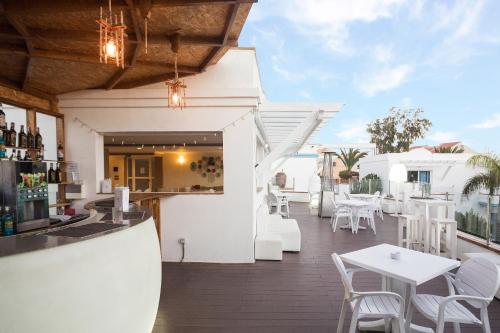 a restaurant with a bar and white tables and chairs at Hotel Arena Beach in Corralejo
