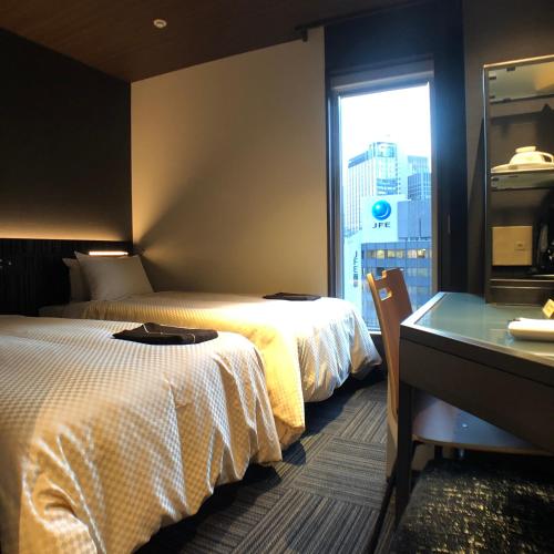 a hotel room with two beds and a desk and a window at JHotelTokyoGEO in Tokyo
