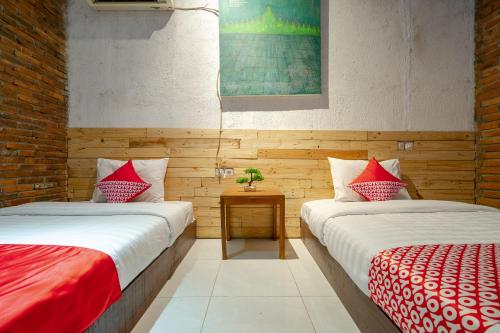 a room with two beds with red and white sheets at OYO 2380 Alea Guesthouse in Borobudur
