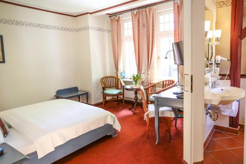a bedroom with a bed and a desk and a table at Altstadthotel Twardokus in Aurich