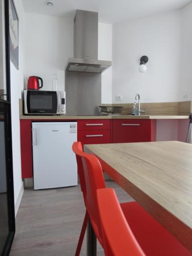 a kitchen with a wooden table and a white refrigerator at Hotel le Faisan in Saint-Avertin