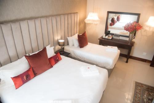two beds in a hotel room with a mirror at Potch Manor Boutique Guest House in Potchefstroom