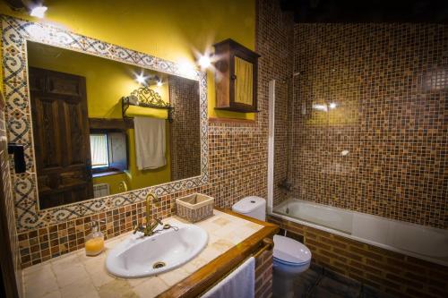 y baño con lavabo, aseo y espejo. en Casa rural La Tenada, en Los Narros