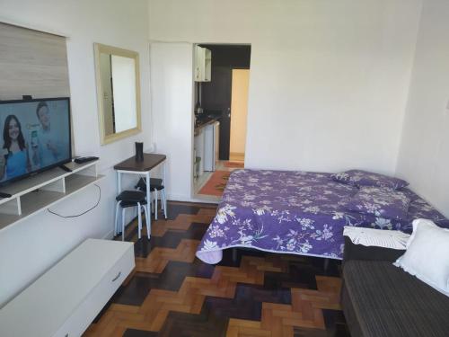 a bedroom with a purple bed and a television at Apartamento Paraíso A Beira Mar in Torres