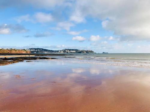 a beach with a reflection of the sky in the water at BEACHES - South Sands beach house in Torquay