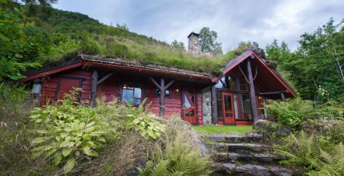 ein rotes Haus mit einem Grasdach mit einem Hügel in der Unterkunft Troll Fjordhytter in Syvde
