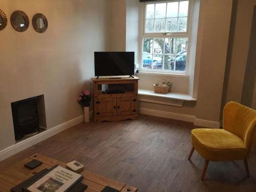 a living room with a television and a chair and a table at Country Retreat in Highpeak Junction
