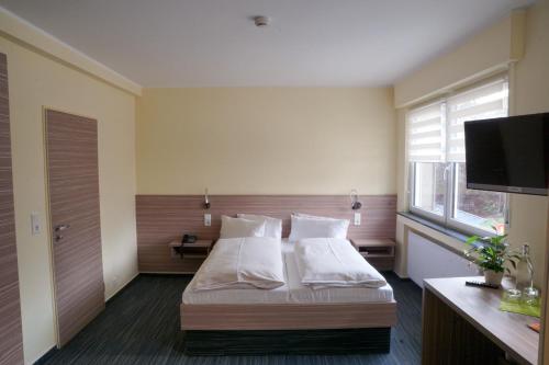 a bedroom with a bed and a flat screen tv at Hotel Zur Heide in Aachen