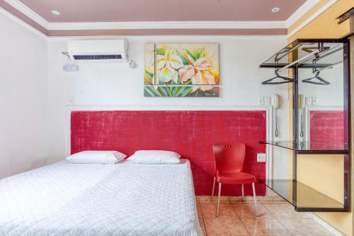 a bedroom with a bed and a red wall at Ouro Hotel in Vespasiano