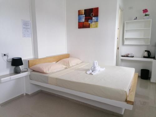 Un dormitorio blanco con una cama con un osito de peluche. en Astillo's Guest Houses en Moalboal