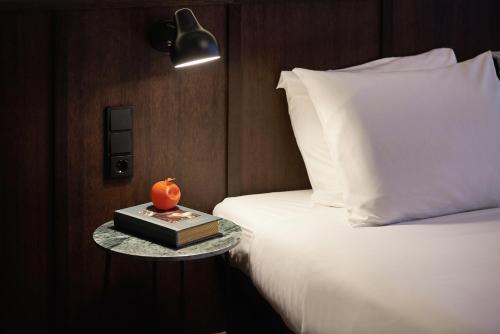 a bed with a table with a book and a lamp at Hotel Mariënhage in Eindhoven