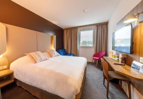 een hotelkamer met een groot bed en een bureau bij Campanile Findrol Annemasse Savoie Leman in Fillinges