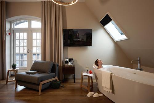 a woman sitting in a bath tub in a bathroom at Hotel Mariënhage in Eindhoven