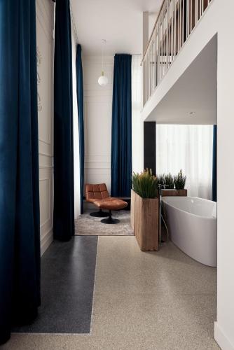 a bathroom with a tub and a staircase with blue curtains at Hotel Mariënhage in Eindhoven