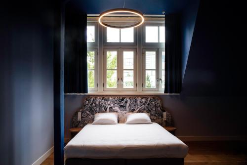 a bed in a blue room with a window at Hotel Mariënhage in Eindhoven