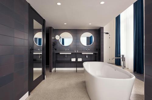 a bathroom with a large tub and a large mirror at Hotel Mariënhage in Eindhoven
