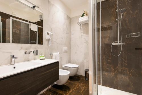 y baño con aseo, lavabo y ducha. en Hotel Regent - In pieno Centro, en San Benedetto del Tronto