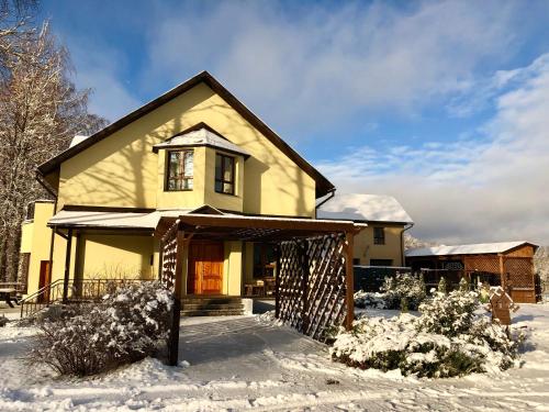 una casa amarilla con nieve en el suelo en Rudzupuķes en Svente