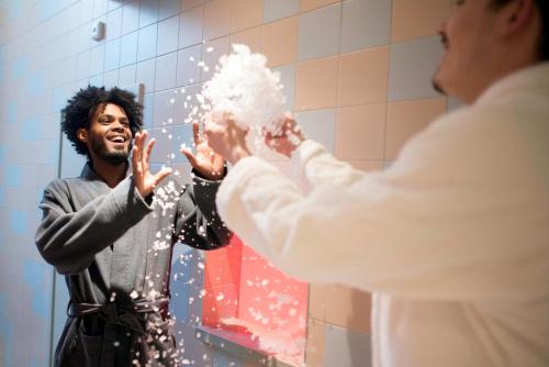a man standing in front of a mirror spraying a woman at The Green Elephant Hostel & Spa in Maastricht