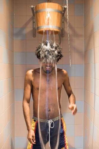 a man in a shower with a bucket on his head at The Green Elephant Hostel & Spa in Maastricht