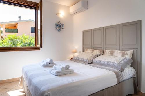 1 dormitorio con 1 cama blanca grande y toallas. en Villa Laura en Villaputzu