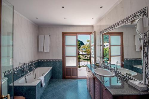een badkamer met 2 wastafels, een bad en een grote spiegel bij Mitsis Galini in Kamena Vourla