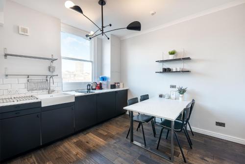 a kitchen with black cabinets and a table with chairs at HSA - Shoreditch in London