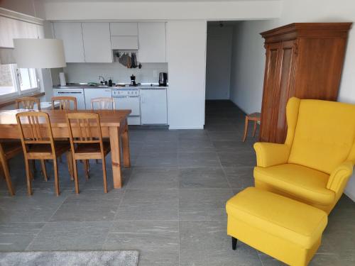 a kitchen with a dining table and a yellow chair at Ferienwohnung in Trin in Trin