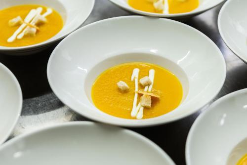 a bowl of orange carrot soup with a fork in it at Burbiskio dvaras in Anykščiai