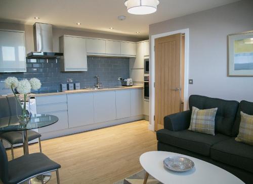 a kitchen and living room with a couch and a table at Alpha Spa classic 1 bedroom apartment in Harrogate