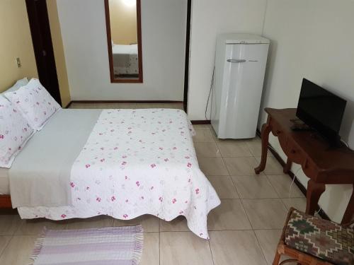 a bedroom with a bed and a desk and a television at Aruá Suítes in Praia do Forte