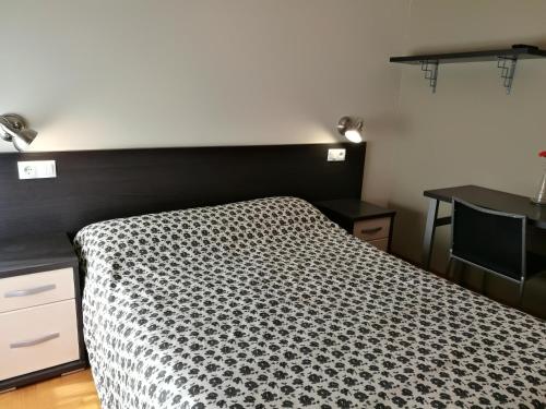 a bedroom with a bed with a black and white comforter at Pension Santiago in Burgos