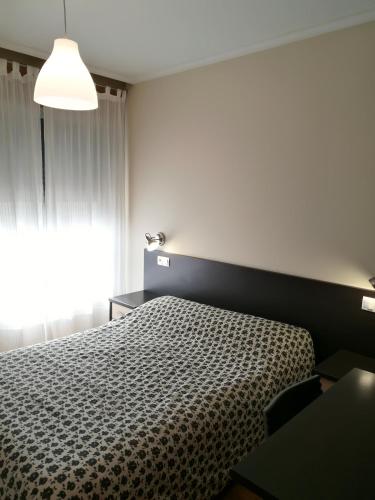 a bedroom with a bed and a window at Pension Santiago in Burgos