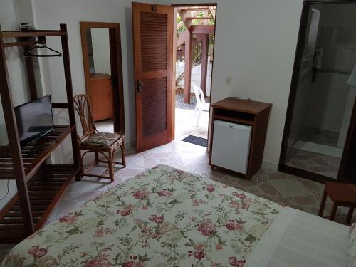 a room with a bed and a table and a door at Aruá Suítes in Praia do Forte