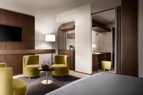 Habitación de hotel con sillas verdes y escritorio. en Speronari Suites, en Milán