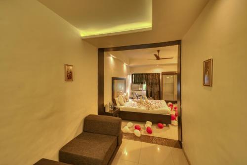 a bedroom with a bed and a chair and a mirror at Hotel Ashwin Igatpuri, Pure Veg & Jain Food in Igatpuri