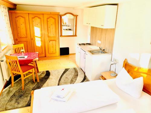 eine kleine Küche mit einem Tisch und einem weißen Kühlschrank in der Unterkunft Gutshof zum Schluxen in Pinswang