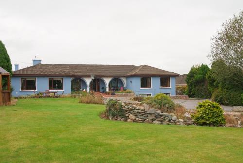 una casa azul con una pared de piedra en el patio en Gormans Country Home en Killarney