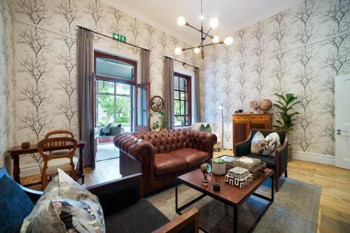 a living room with a leather couch and a table at Bonne Esperance Boutique Guest House in Stellenbosch
