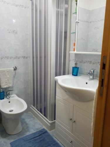Baño blanco con lavabo y aseo en GRAZIOSA casa vacanze tra sheraton hotel e baia verde hotel, en Aci Castello