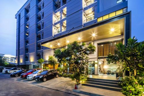 a building with cars parked in a parking lot at Aliz Hotel in Nonthaburi